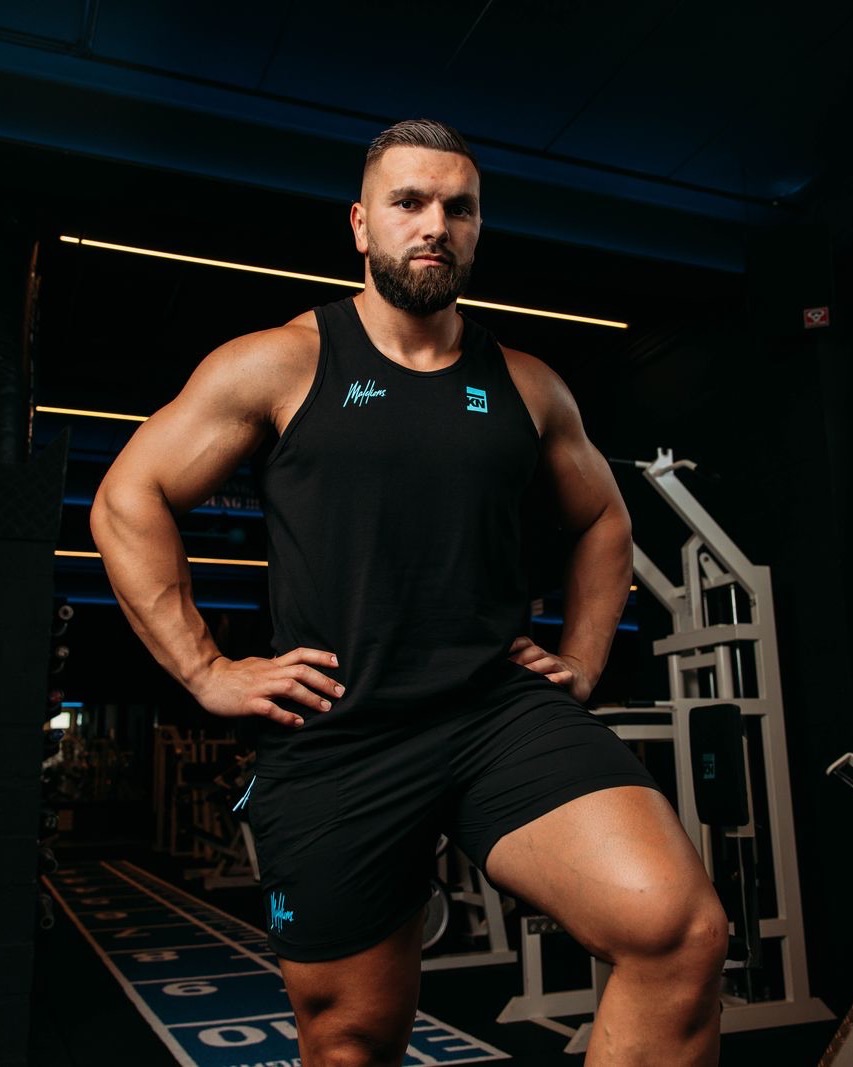 Kosso in de sportschool in een Kosso Nutrition-tanktop, uit de shoot van de Kosso x Malelions-collectie.